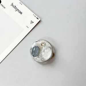 Macro detail of the round phone grip featuring gray-blue stone textures and silver foil
