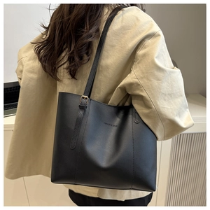 Detail of the black leather tote bag featuring Fashion & Bags embossed logo and strap buckle
