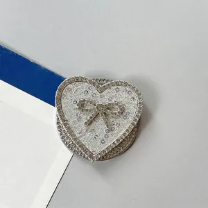 Detalle del soporte para móvil en forma de corazón con pedrería y lazo de cristal