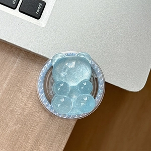 Detail of light blue glittery bear phone grip with pearl-embellished round base on desk