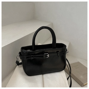 Close-up of glossy black bucket bag with silver buckle and sleek curved handle