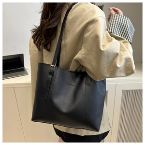 Detail of black leather tote bag with debossed fashion logo and adjustable strap