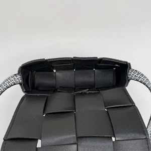 Close-up of black woven leather crossbody bag showing inner space and geometric strap