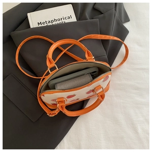 Top-down view of orange strawberry handbag showing interior space with phone and wallet
