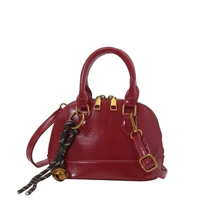 Deep red shell-shaped handbag with crocodile pattern and golden bell pendant accessory