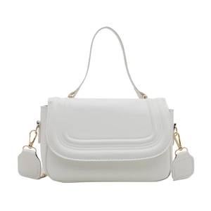 Minimalist white leather crossbody bag with curved stitching and gold hardware on white background