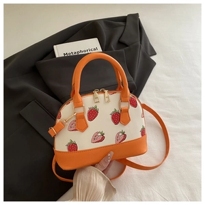 Close-up of shell-shaped crossbody bag with strawberry print and contrast leather