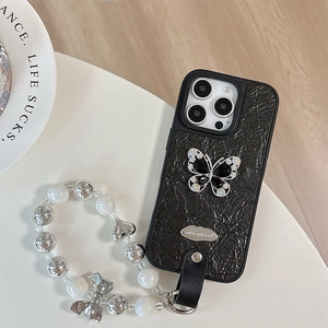 Macro view of black crinkled texture phone case with rhinestone butterfly and pearl strap
