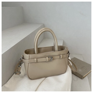 Detail of apricot bucket bag with double handles and metal buckle on stone surface