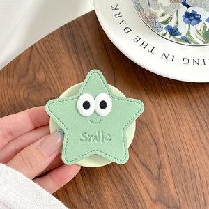 Détail macro du support de téléphone étoile vert avec yeux et gravure Smile sur cuir
