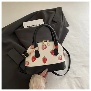 Detail of shell-shaped handbag with strawberry print and black contrast panels