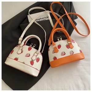 Detail of strawberry print shell bags in cream and orange colors with gold hardware