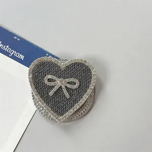 Detalle de soporte de corazón para móvil con diamantes y lazo negro textura cuero