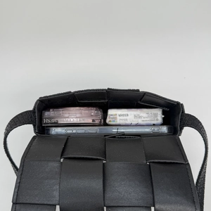 Detail view showing spacious interior of black woven crossbody bag with daily essentials