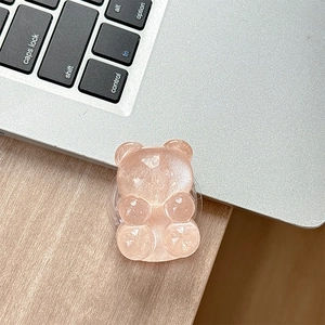 Detail of pink translucent bear phone grip with pearlescent glitter on a laptop surface