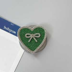 Detalle del soporte de móvil corazón verde con pedrería brillante y lazo de cristal