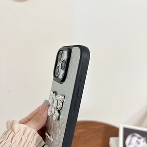 Detail of silver leather iPhone case featuring a 3D rhinestone butterfly and metal chain