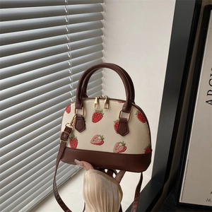 Chic beige strawberry print shell handbag with dark brown handles and adjustable strap