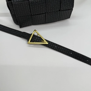 Detail of woven black handbag featuring a signature gold triangle metal buckle and strap