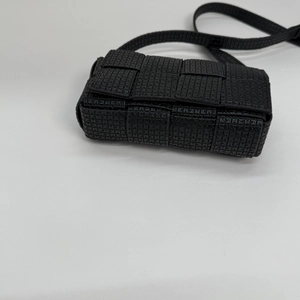 Top-down view of black woven crossbody bag featuring textured flap and slim strap