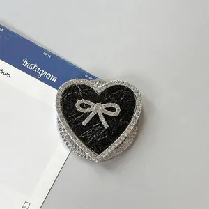 Detalle del soporte de móvil de corazón con cuero negro y lazo de pedrería plateada