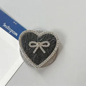 Detalle macro de soporte para móvil de corazón con lazo de diamantes y purpurina