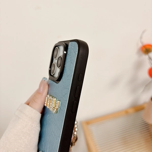 Detail of blue leather iPhone case with crystal Miu emblem and precise side button cutouts