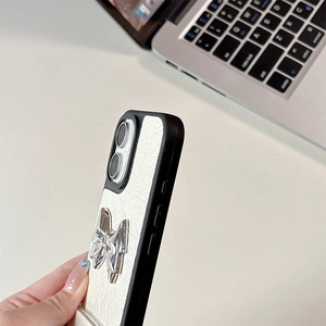 Detail of white wrinkled leather phone case with silver metal bow and black bumper