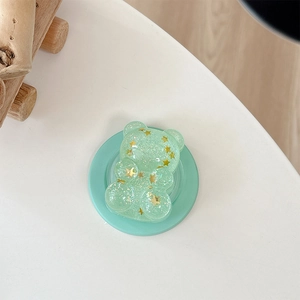 Macro shot of mint green bear phone grip with sparkling gold star sequins and glitter