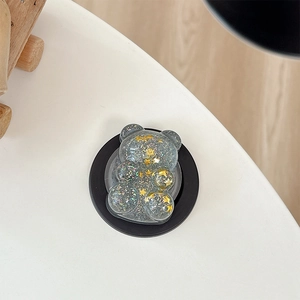 Detail of bear phone stand with gold star sequins and silver glitter in clear resin