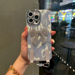 Detail of silver bow rhinestone inlay on transparent iPhone case with braided wrist strap