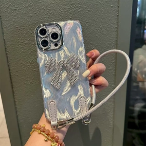 Detail of silver phone case with a large diamond bow and matching braided hand strap