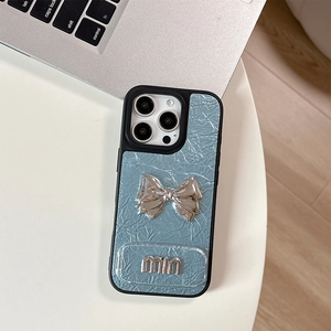 Detail of light blue wrinkled leather phone case with silver metallic bow and min logo