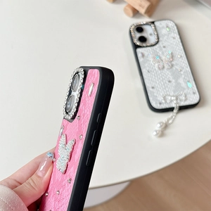 Close-up of luxury phone case with diamond butterfly, pearl pendant, and camera ring lens