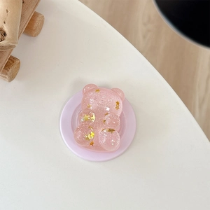 Pink glitter bear phone socket with golden star sequins on a white surface