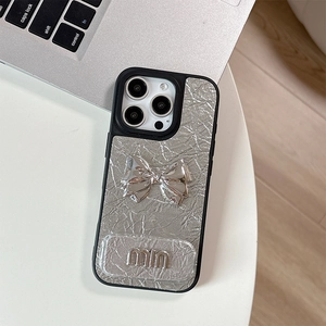 Close-up of silver crinkled leather iPhone case featuring a 3D bow and mirror detail