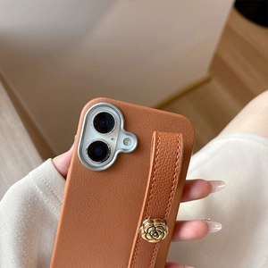Detail of brown lychee leather iPhone case with hand strap and golden camellia ornament