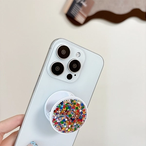 Close-up of a circular phone grip featuring colorful sequins and glitter on a blue phone