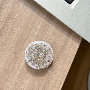 Close-up of a round glitter phone socket with silver and pink sequins on wood desk