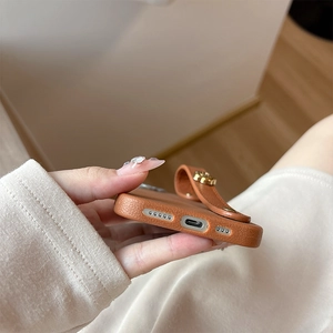Detail of brown litchi texture leather phone case with metal flower hand strap for iPhone