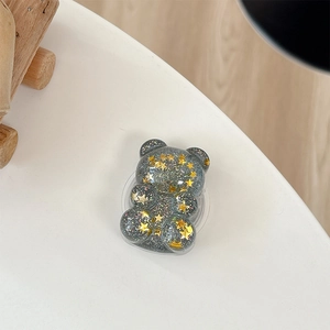 Detail view of a glittery bear phone stand with golden stars and silver sequins