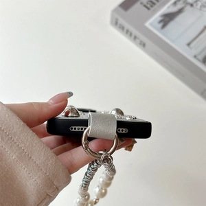 Détail de la coque iPhone noire avec crochet en métal argenté et bracelet en perles