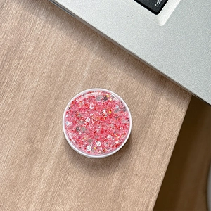 Macro detail of round pink glitter phone socket holder on a wooden desk setup