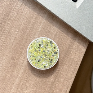 Close-up of a round phone socket with green glitter and sequins on a wooden desk