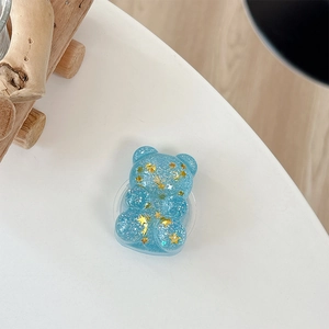 Detail view of light blue glitter bear phone stand with golden star sequins and sparkles