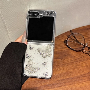Detail view of transparent flip case with sparkling rhinestone butterfly and glitter accents