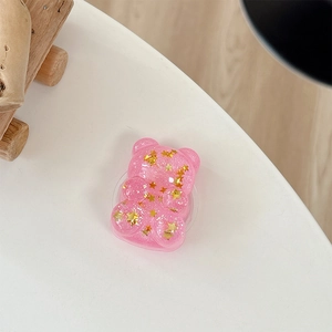 Macro detail of a pink translucent bear phone grip filled with golden star sequins