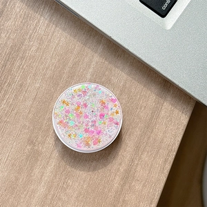 Macro view of round glitter phone socket with pink sequins on a light wooden desk