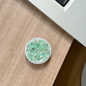 Macro view of a circular phone socket with green glitter on a light wood desk