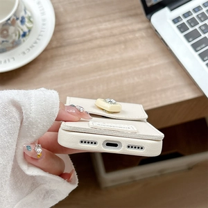 Détails de la coque en cuir crème avec porte-carte en strass et découpes précises du port